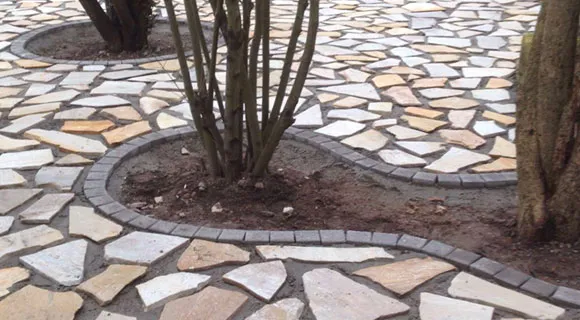 verlegtes Natursteinmosaikmuster mit Strauch in Beet