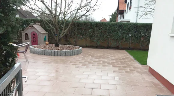 mit rotem Sandstein verlegte Nutzfläche mit einem Ringbeet