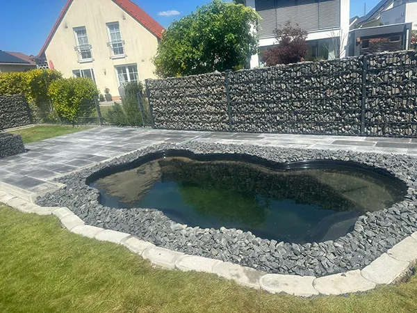 Gartenteich mit angeschlossener, grau gepflasterter Terrasse