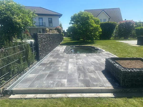 Gartenteich mit angeschlossener, grau gepflasterter Terrasse