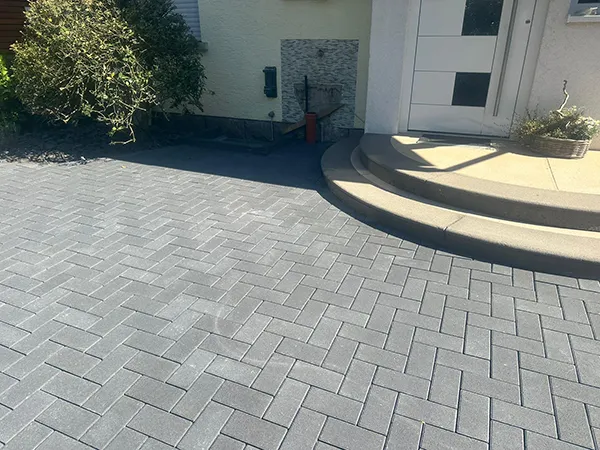 Einfahrt und Hauseingang mit grauen Pflastersteinen